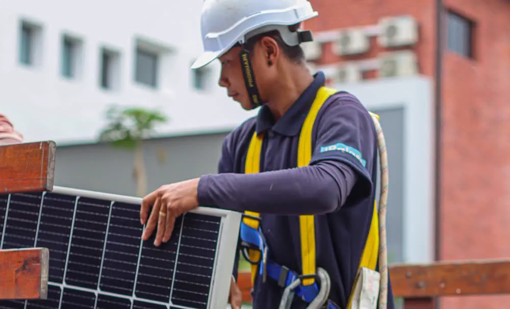 Pekerja De Solar mengangkat panel solar naik ke bumbung