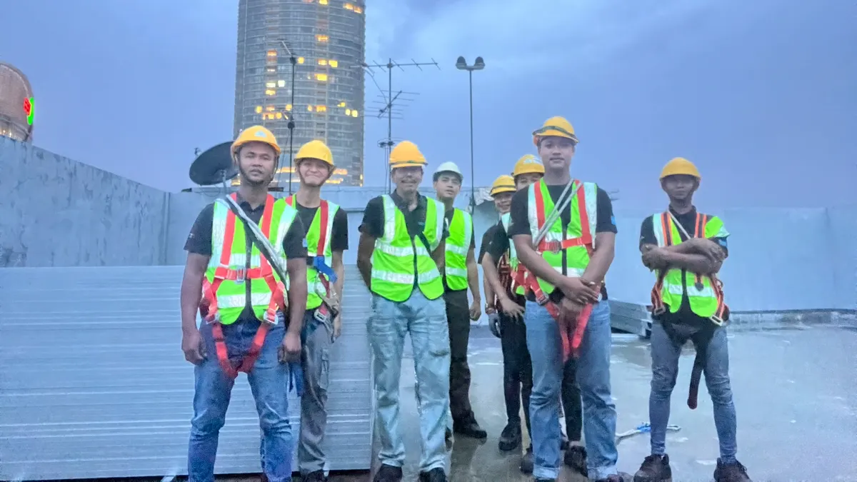 Pasukan pemasangan De Solar bergambar atas bumbung selepas kerja, lengkap dengan topi keledar dan tali keledar